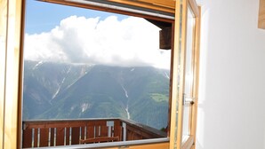 A room with a large window overlooking a mountainous landscape. - Ambiente B21 (Bettmeralp)