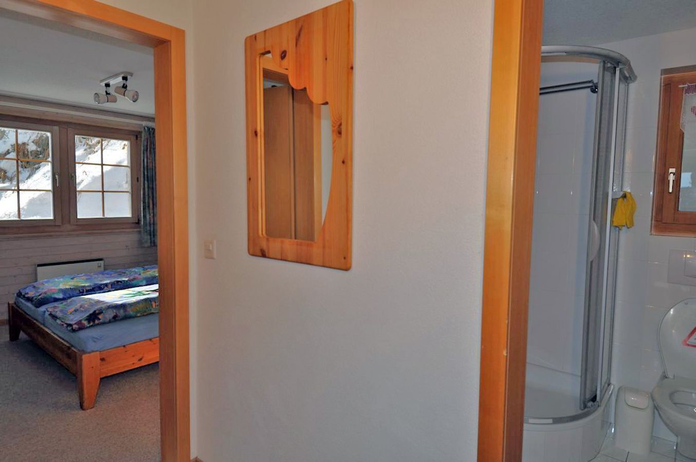 A bedroom with a bed, a wooden door, and a bathroom with a shower.