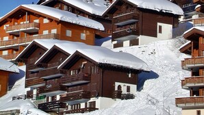 Un complejo turístico de montaña nevado con edificios de madera y una iglesia.