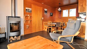 Interior acogedor de una cabaña con estufa de leña, muebles de madera y un comedor.