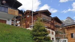 Un edificio de madera de varios pisos con balcones, con montañas al fondo.