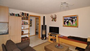 Una sala de estar con sofá, televisión, chimenea, estantería y un cuadro en la pared.