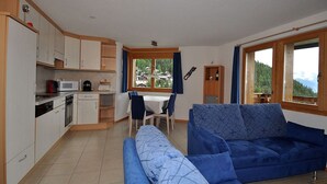 A compact living space with a kitchenette, dining area, and a sofa. - Camelot 4 (Bettmeralp)