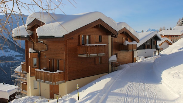 A wooden chalet with a balcony, surrounded by snow-covered mountains. - Camelot 4 (Bettmeralp)