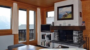 Tunnelmallinen olohuone, jossa on kivinen takka, televisio ja kirjahylly.