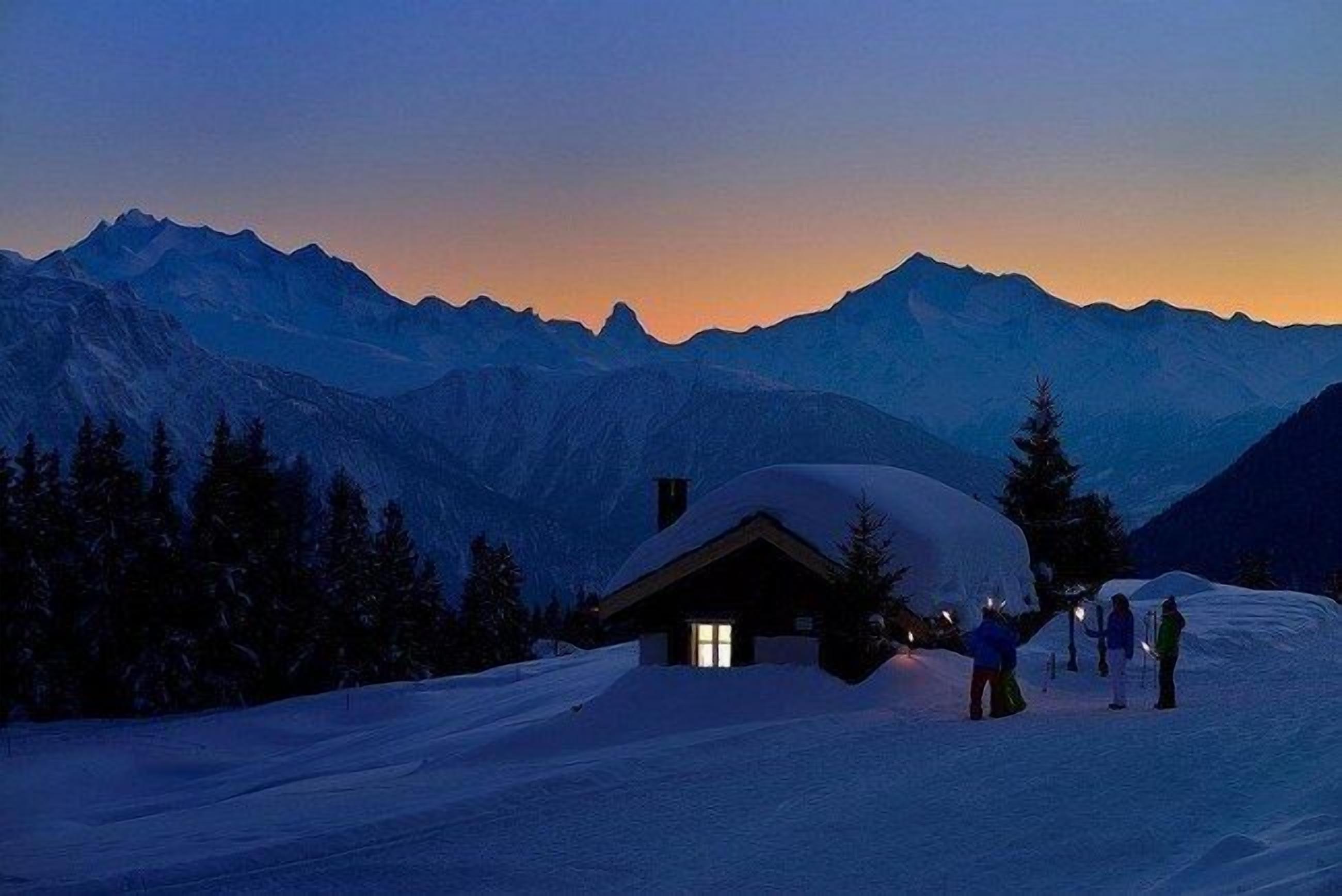 A snow-covered mountain landscape with a cabin and skiers.