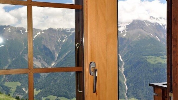 Een houten deur met uitzicht op een berglandschap door een raam.