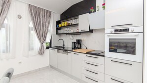A modern kitchen with white cabinets, a black countertop, and a built-in oven. - Apartment Ana With Private Pool (Solin)