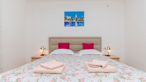 A bedroom with a bed, two nightstands, two lamps, and a painting on the wall. - Apartment Ana With Private Pool (Solin)