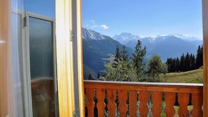 A balcony with a view of snow-capped mountains and a clear blue sky. - Harpa OG (Bettmeralp)