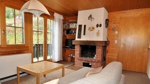 A cozy cabin interior with a fireplace, wooden furniture, and a bookshelf. - Jadwiga OG (Bettmeralp)