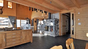 Ein großzügiger Holzraum mit Kamin aus Stein, Holzschränken und Essbereich.