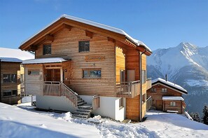 A wooden mountain lodge with a staircase leading to the entrance, a balcony, and a view of snow-covered mountains. - Laackerhof (Bettmeralp)