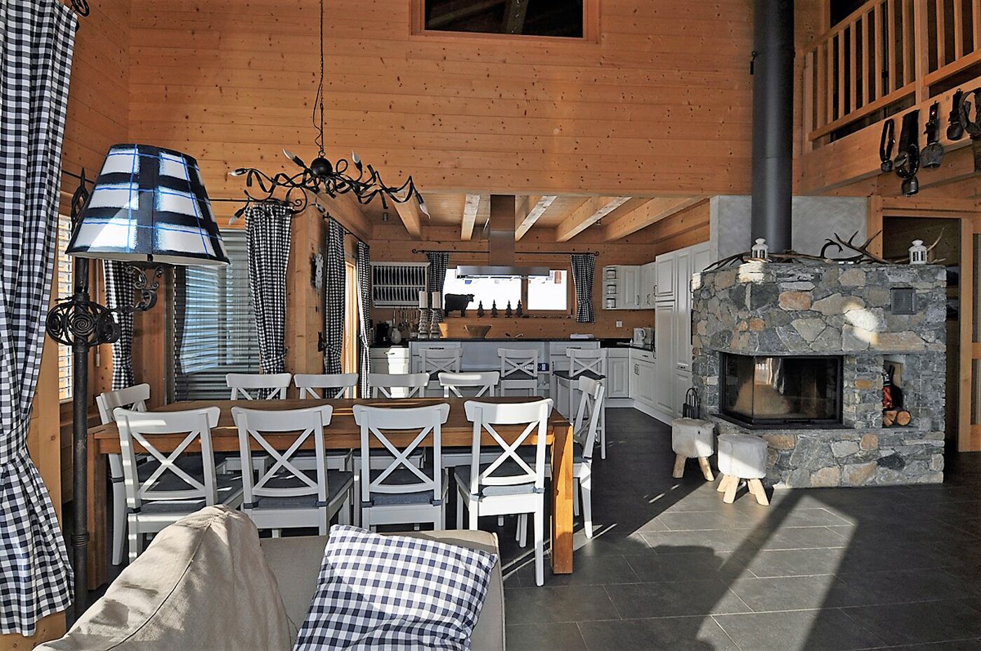 A cozy cabin interior with a dining area, kitchen, and stone fireplace.