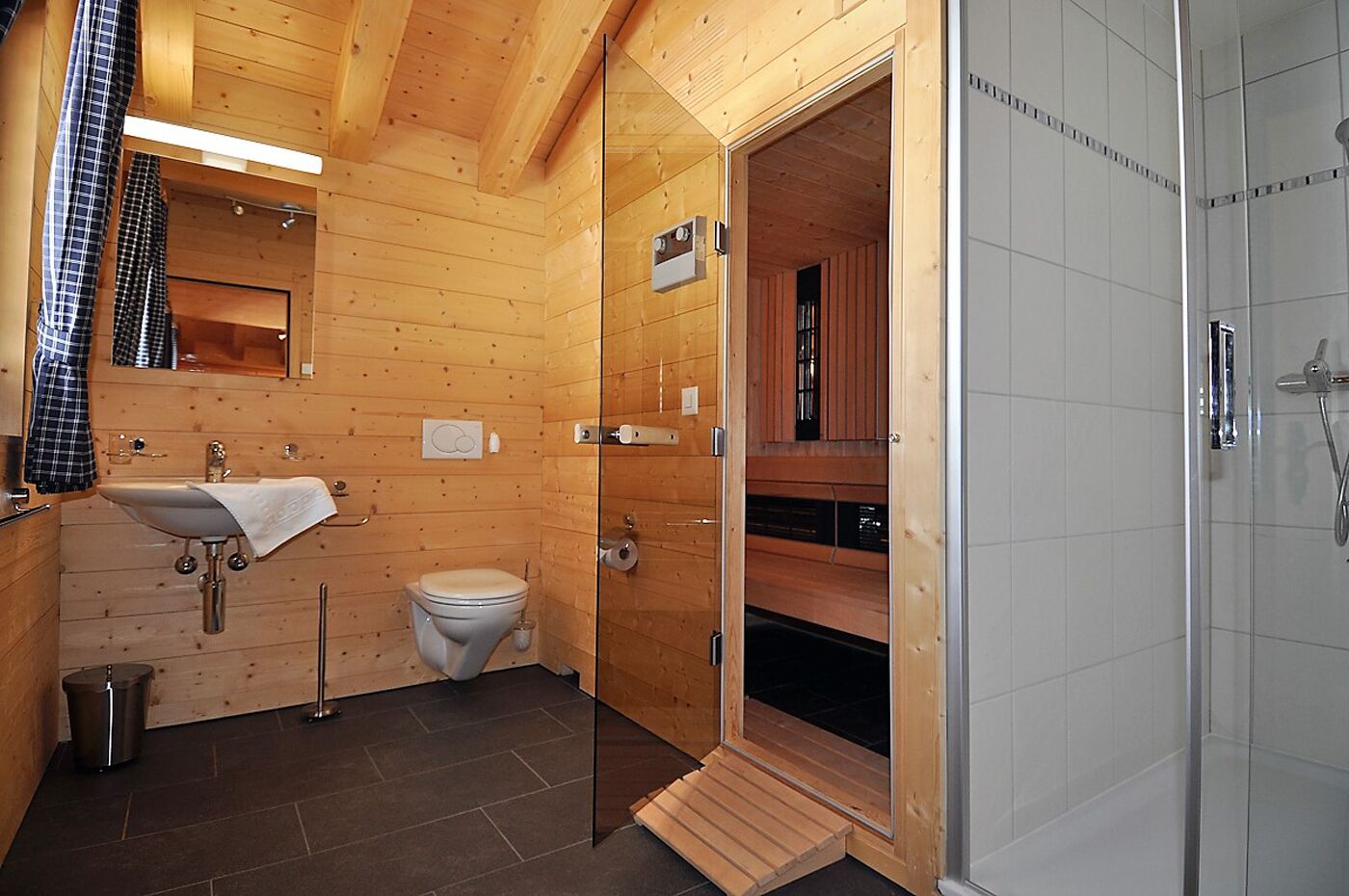 A wooden cabin bathroom with a sink, toilet, and shower.