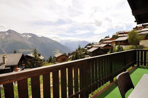 Un balcón con vistas a una cadena montañosa y una hilera de chalets de madera.