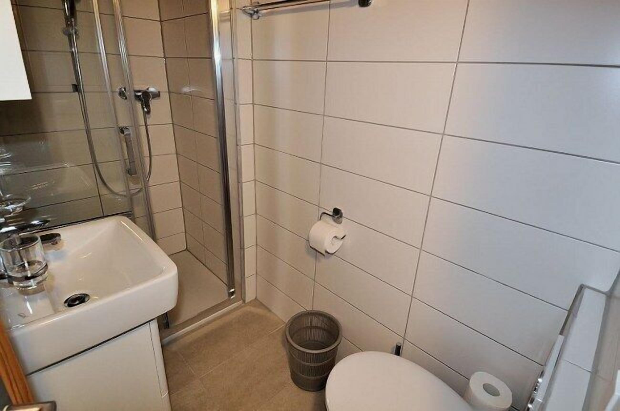A small bathroom with a sink, toilet, and shower.