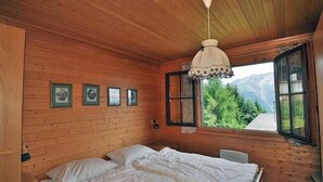 Un dormitorio de cabaña de madera con una cama, una lámpara colgante y cuadros en la pared.