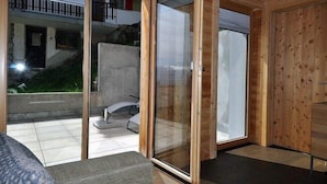 Ein modernes Interieur mit einer Schiebetür zum Außenbereich, einer eingebauten Sitzbank und einer Holzwand.