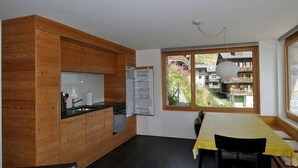 Eine moderne Küche mit Holzschränken, einem eingebauten Ofen und einem Essbereich mit Tisch und Stühlen.