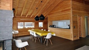 A wooden interior with a dining table, chairs, and a kitchen area. - Nachtigall OG (Bettmeralp)