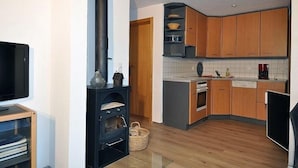 Une cuisine compacte avec des meubles en bois, un four encastré et un four à micro-ondes.