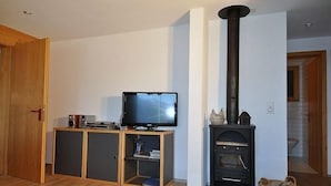 Un salon équipé d’un téléviseur, de meubles en bois et d’un poêle à bois noir.