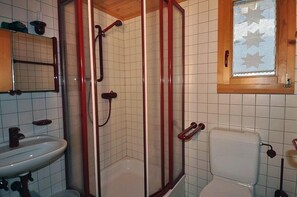 A bathroom with a shower enclosure, a toilet, and a sink. - Sternschnuppe OG (Bettmeralp)