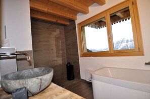 A bathroom with a stone basin, a shower, and a bathtub. - t'Alpa (Bettmeralp)