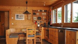 L’intérieur d’une cabane en bois comprend un coin repas, une cuisine et de grandes fenêtres.
