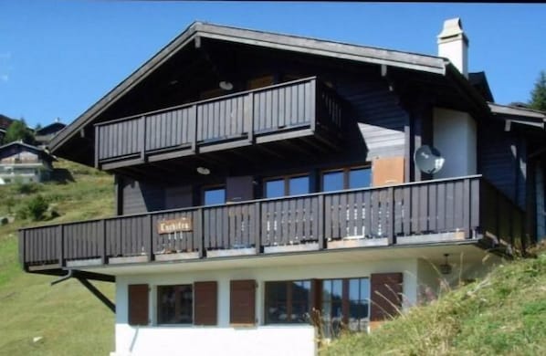 A two-story chalet with a balcony and a satellite dish.