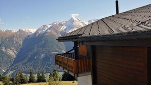 Een houten chalet met balkon en uitzicht op een bergachtig landschap.