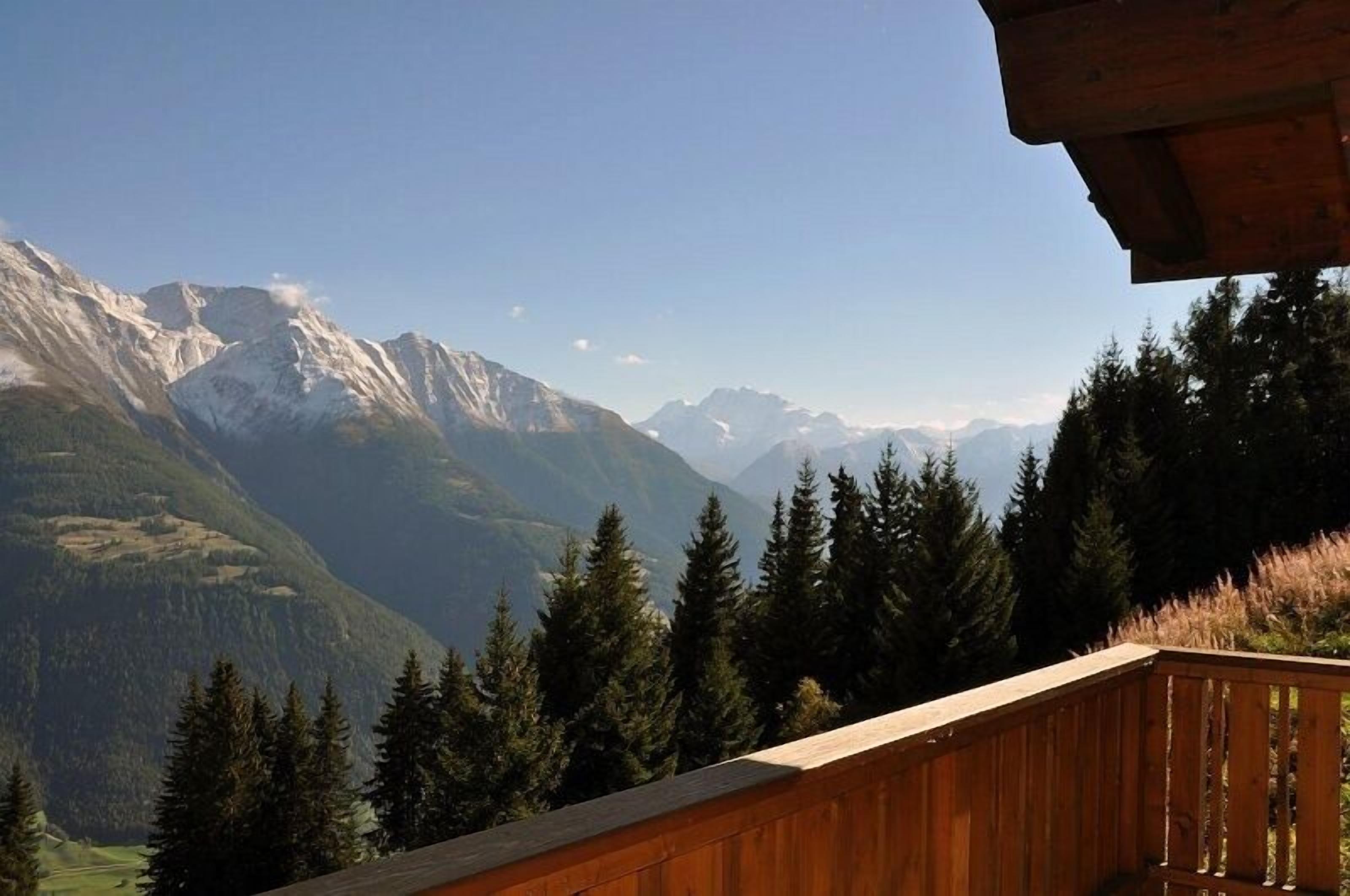 A mountain view from a wooden balcony with a clear sky.