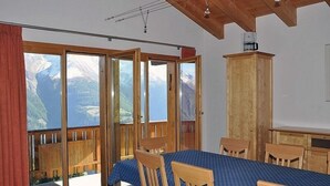 Een kamer met een bed, houten meubels en uitzicht op bergen door grote ramen.