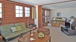 Ein gemütliches Wohnzimmer mit einem grünen Sofa, einem Holztisch und einem Fernseher.
