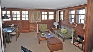 Ein gemütliches Blockhaus-Interieur mit Essbereich, einer Couch, einem Couchtisch und einem Bücherregal.