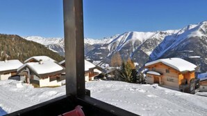Eine Berglodge mit Blick auf schneebedeckte Gipfel und einen klaren Himmel.