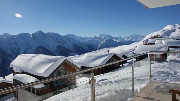 A snow-covered mountain resort with wooden cabins and a clear view of the mountains. - Bella Vista (Fiesch)