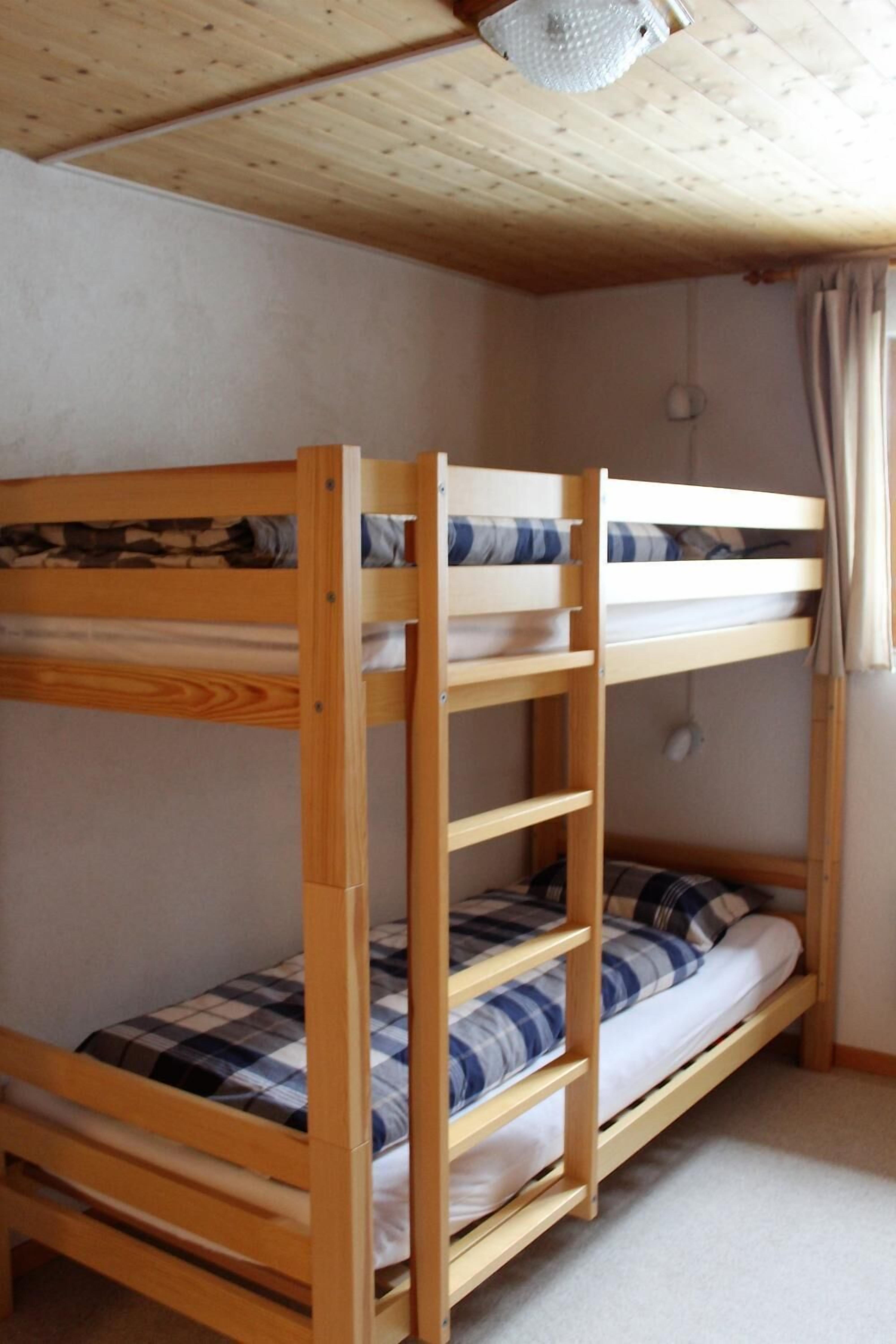 A bunk bed with wooden frames and blue and white bedding.