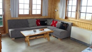 Une pièce chaleureuse avec un canapé gris, une table basse en bois et un radiateur.