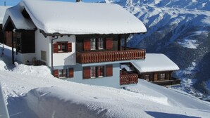 Un chalet enneigé doté d’un balcon et offrant une vue sur la montagne.