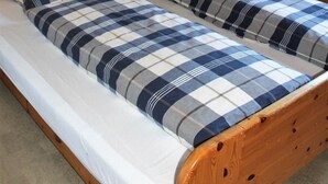 Une chambre dans un chalet en bois, avec deux lits, une table de chevet, une lampe et une photographie encadrée représentant un pont.