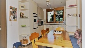 Una cocina compacta con armarios blancos, una mesa de comedor de madera y un horno empotrado.