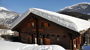 A wooden cabin with a snow-covered roof, set against a mountainous backdrop. - Carpe Diem 2 (Fiesch)