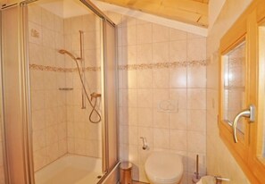 Un baño con ducha, inodoro y puerta de madera.