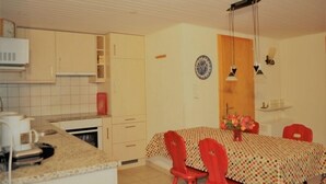 A compact kitchen with a dining area, featuring a microwave, a coffee maker, and a table with chairs. - De Hooghe Stee (Fiesch)