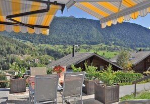 A terrace with chairs and a table, overlooking a mountainous landscape with houses. - De Hooghe Stee (Fiesch)
