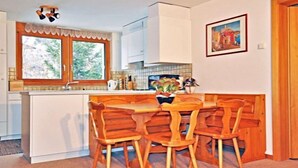 Una cocina con una isla central, sillas de madera, un ventanal con vistas a zonas verdes y un cuadro en la pared.