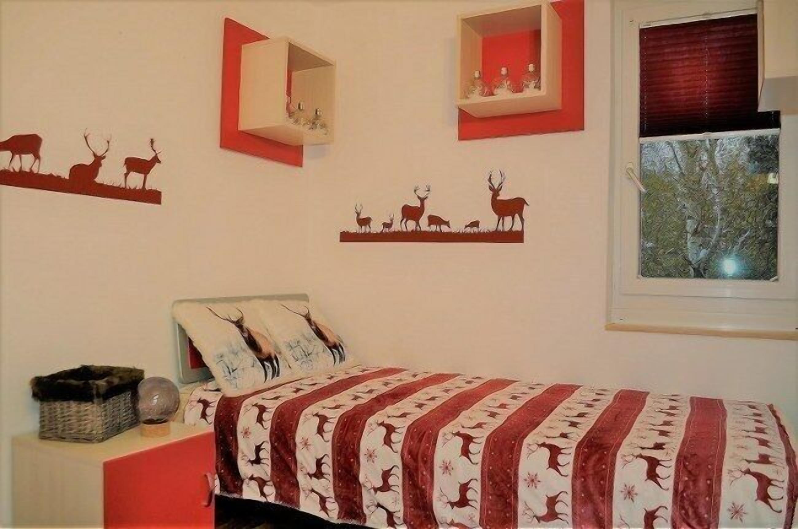 A bedroom with a bed, a nightstand, a window, and wall decorations.