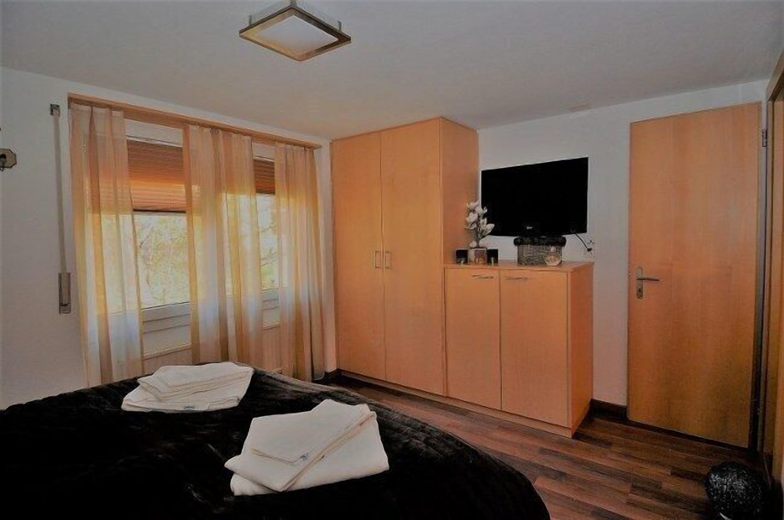 Une chambre à coucher avec un lit, une armoire en bois et un téléviseur à écran plat.